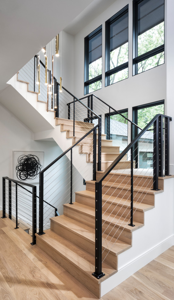 Photo of a large contemporary wood u-shaped staircase in Minneapolis with wood risers and cable railing.