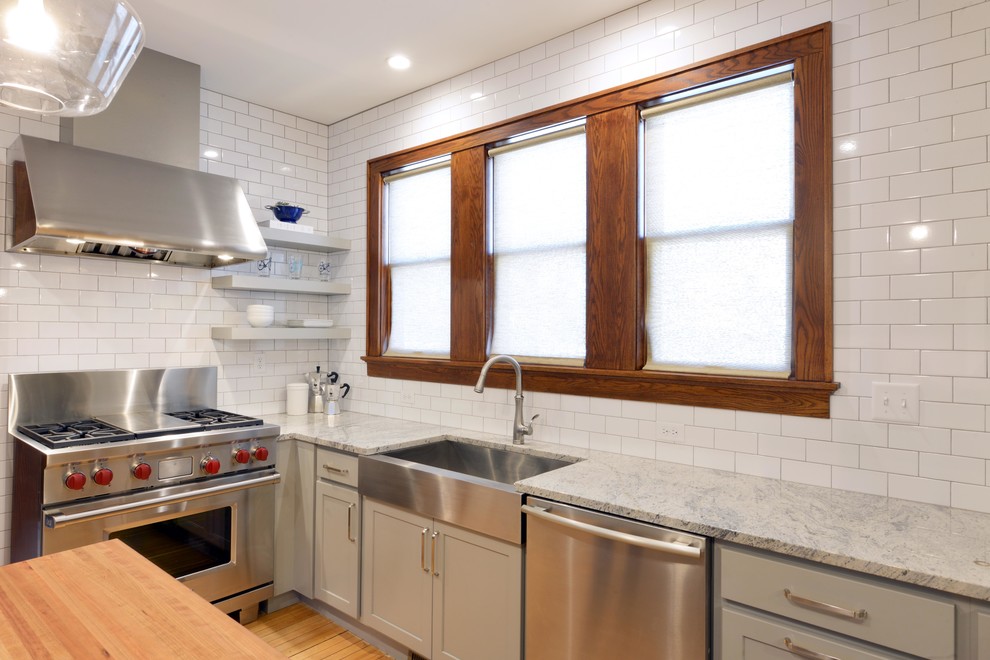 Enclosed kitchen - mid-sized transitional light wood floor and brown floor enclosed kitchen idea with a farmhouse sink, shaker cabinets, gray cabinets, wood countertops, white backsplash, porcelain backsplash, stainless steel appliances, an island and brown countertops