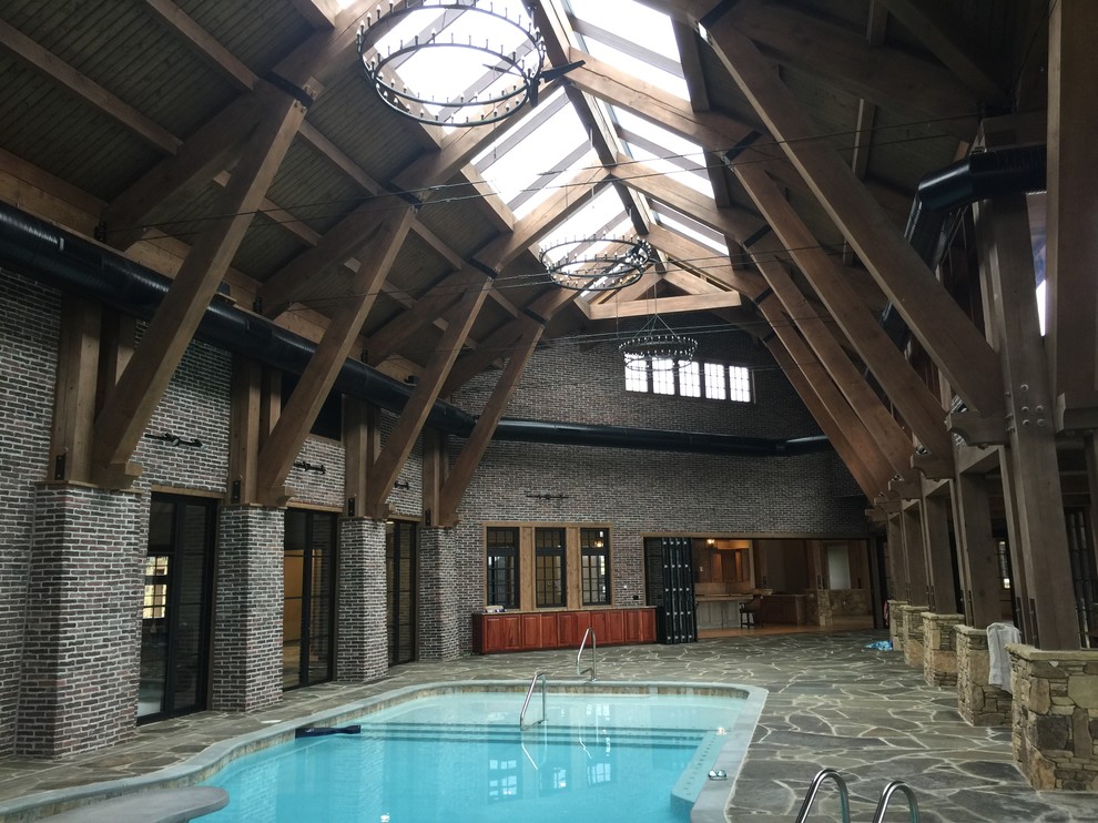 Photo of a large country indoor custom-shaped lap pool in Nashville with a pool house and natural stone pavers.