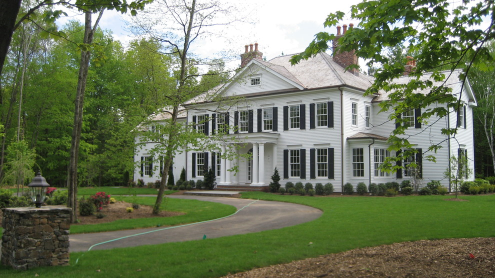 Aménagement d'une façade de maison blanche classique à un étage avec un toit à quatre pans et un toit en shingle.