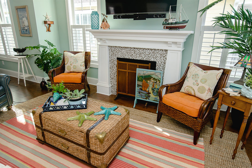 Photo of a mid-sized beach style living room in Other with green walls, medium hardwood floors, a standard fireplace, a tile fireplace surround and a wall-mounted tv.