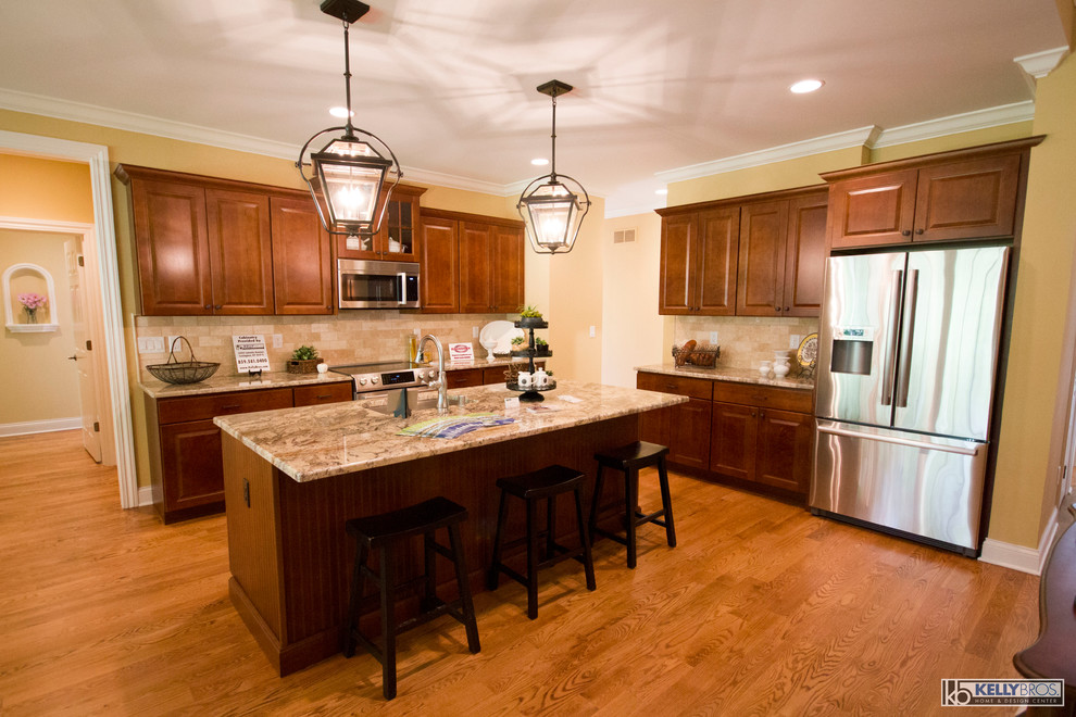 Open concept kitchen - mid-sized transitional l-shaped medium tone wood floor and brown floor open concept kitchen idea in Cincinnati with an undermount sink, raised-panel cabinets, medium tone wood cabinets, granite countertops, beige backsplash, stone tile backsplash, stainless steel appliances and an island