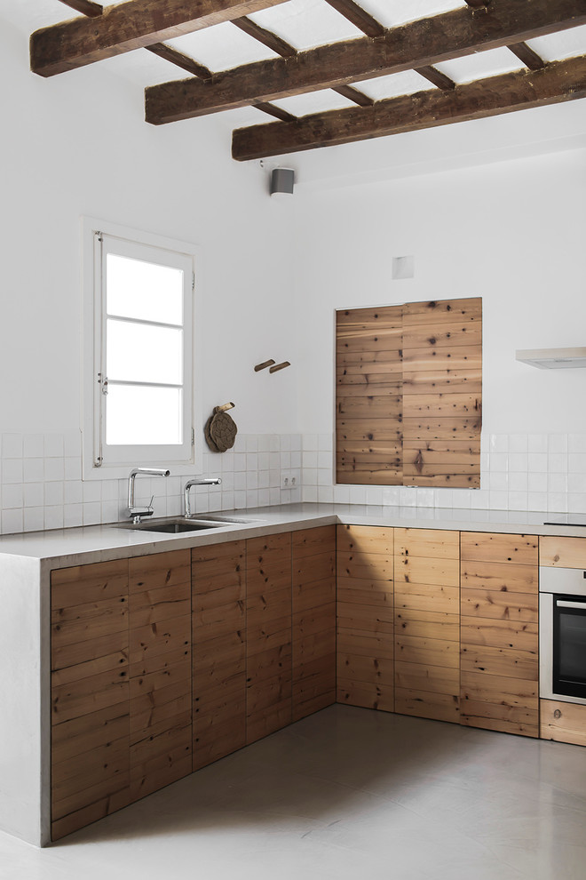 This is an example of a mid-sized country l-shaped open plan kitchen in Barcelona with a double-bowl sink, raised-panel cabinets, medium wood cabinets, white splashback, ceramic splashback, white appliances and no island.