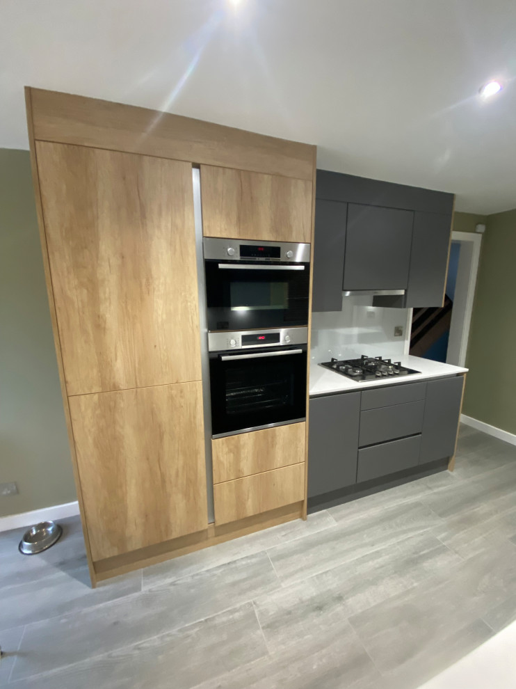Design ideas for a mid-sized contemporary l-shaped eat-in kitchen in Edinburgh with an integrated sink, flat-panel cabinets, grey cabinets, quartzite benchtops, green splashback, glass sheet splashback, black appliances, porcelain floors, no island, grey floor and white benchtop.