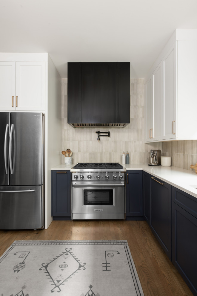 Inspiration for a mid-sized transitional l-shaped eat-in kitchen in Chicago with a drop-in sink, shaker cabinets, white cabinets, quartz benchtops, grey splashback, ceramic splashback, stainless steel appliances, medium hardwood floors, a peninsula, brown floor and white benchtop.