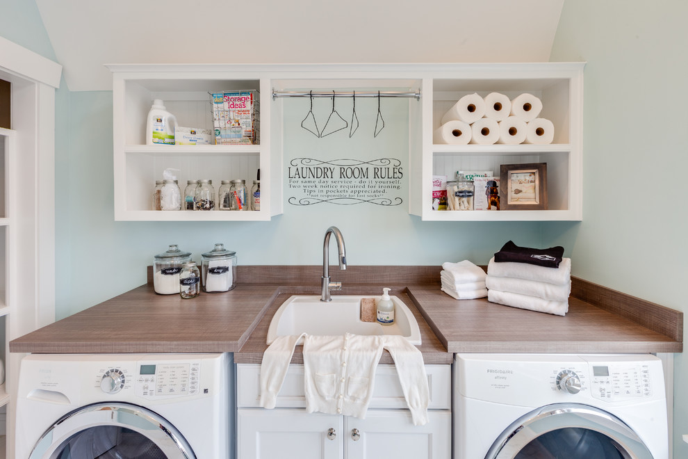 Photo of a large beach style utility room in Other with a drop-in sink, recessed-panel cabinets, white cabinets, laminate benchtops, blue walls, marble floors and a side-by-side washer and dryer.
