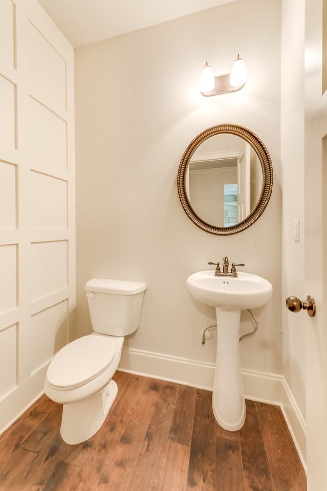Photo of a small transitional powder room in Other with grey walls, medium hardwood floors, a pedestal sink and brown floor.