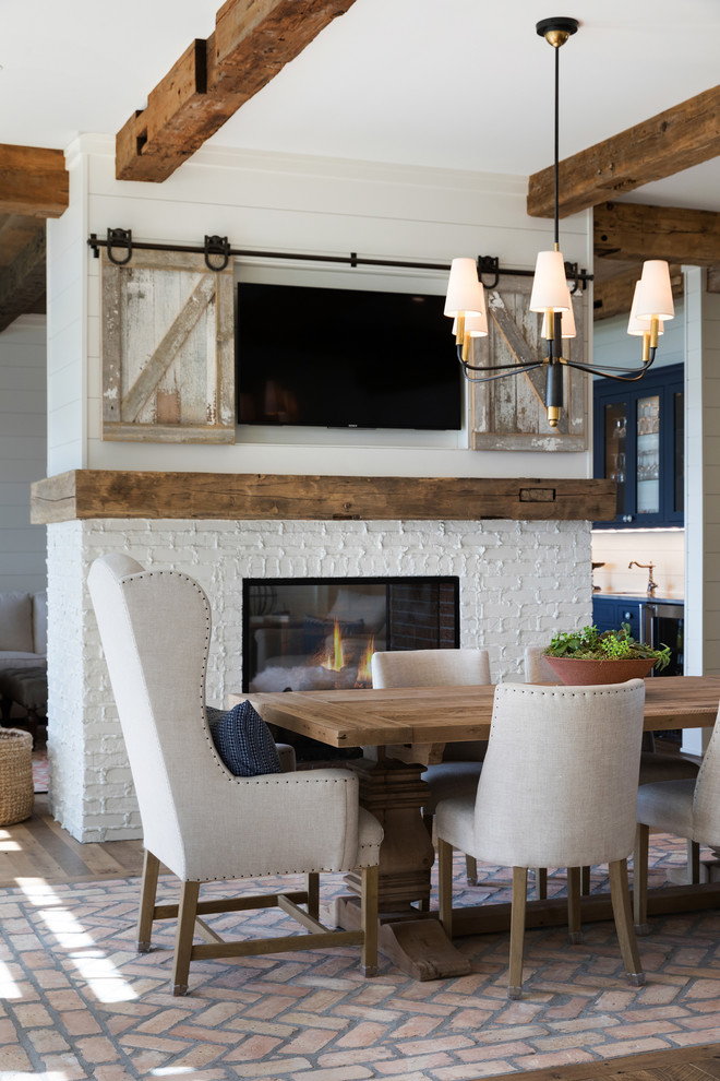 Large beach style kitchen/dining combo in Minneapolis with white walls, medium hardwood floors, a two-sided fireplace, a brick fireplace surround and brown floor.