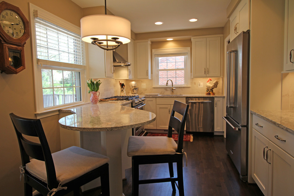 Modern inredning av ett litet kök, med en undermonterad diskho, släta luckor, vita skåp, bänkskiva i kvarts, flerfärgad stänkskydd, stänkskydd i keramik, rostfria vitvaror, mörkt trägolv, en halv köksö och brunt golv