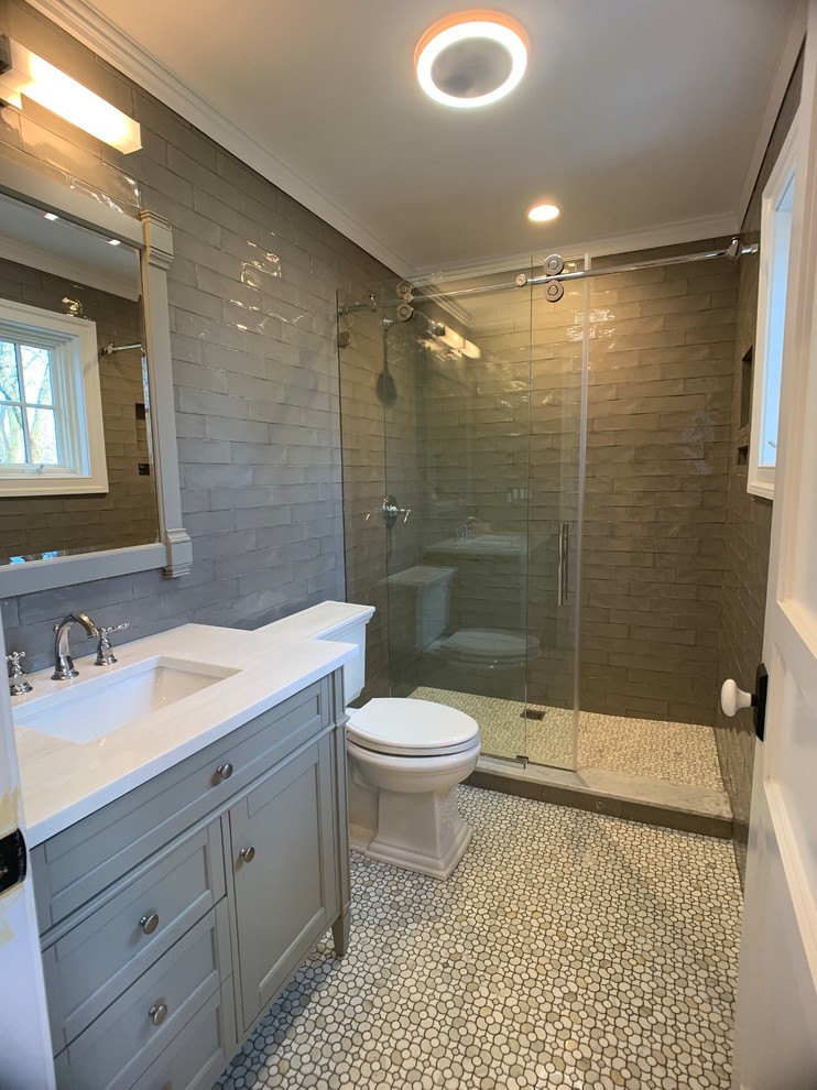 Small transitional 3/4 bathroom in New York with furniture-like cabinets, grey cabinets, an open shower, a one-piece toilet, beige tile, porcelain tile, an integrated sink, quartzite benchtops, a sliding shower screen and white benchtops.
