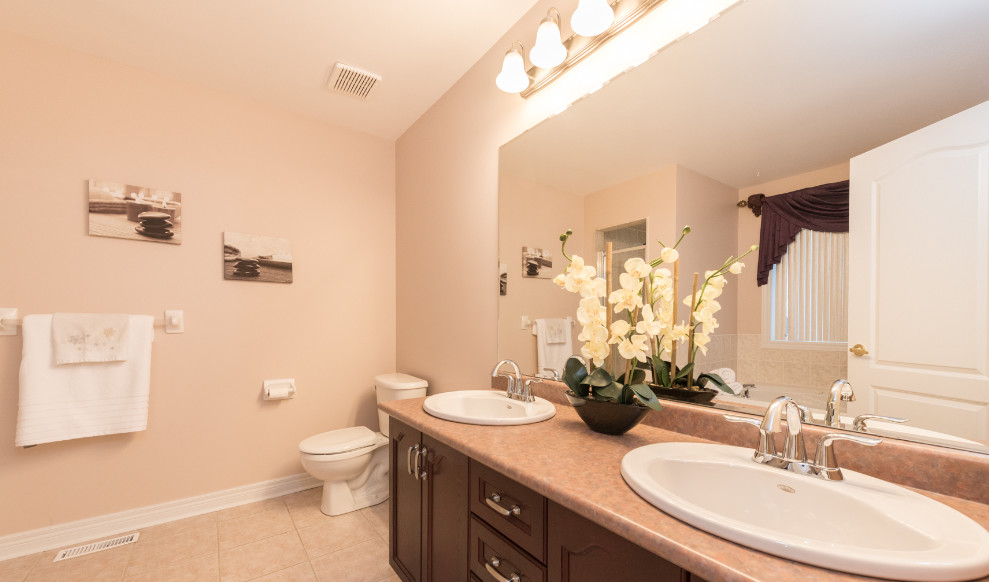 Mid-sized transitional master bathroom in Toronto with recessed-panel cabinets, dark wood cabinets, a drop-in tub, a corner shower, a two-piece toilet, pink walls, ceramic floors, a drop-in sink and laminate benchtops.
