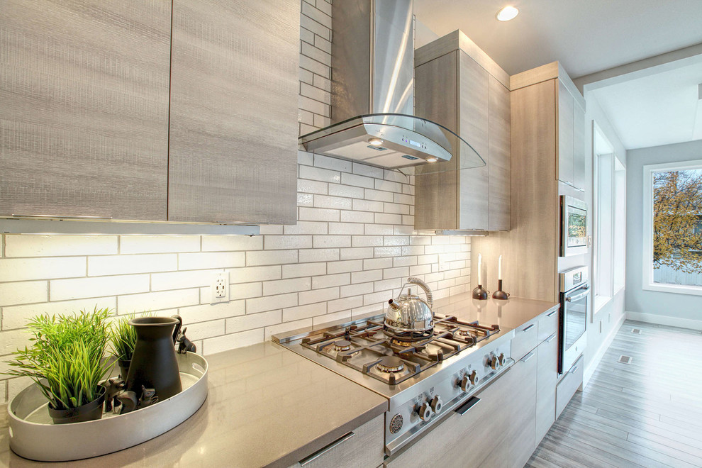 Inspiration for a large modern u-shaped open plan kitchen in Calgary with a double-bowl sink, beige cabinets, quartzite benchtops, white splashback, subway tile splashback, stainless steel appliances, laminate floors and with island.