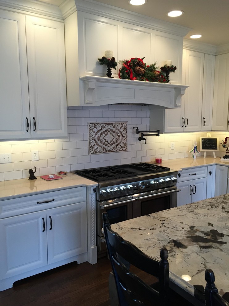 Inspiration for a large transitional u-shaped dark wood floor eat-in kitchen remodel in Indianapolis with an undermount sink, raised-panel cabinets, white cabinets, quartz countertops, white backsplash, subway tile backsplash, stainless steel appliances and an island