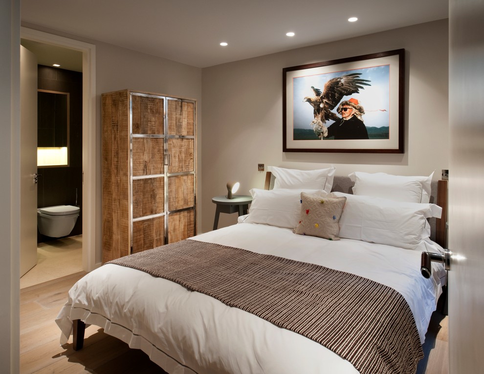 Design ideas for a mid-sized contemporary guest bedroom in London with light hardwood floors and beige walls.