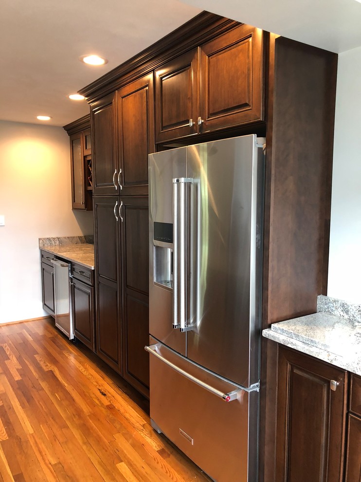 Eat-in kitchen - mid-sized traditional l-shaped light wood floor and brown floor eat-in kitchen idea with an undermount sink, raised-panel cabinets, dark wood cabinets, granite countertops, multicolored backsplash, ceramic backsplash, stainless steel appliances, an island and multicolored countertops