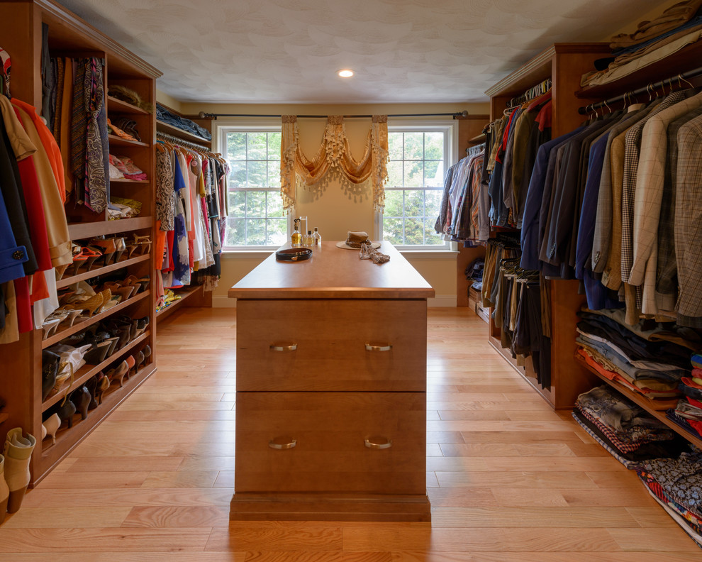 Photo of a transitional gender-neutral walk-in wardrobe in Boston with flat-panel cabinets, light wood cabinets, light hardwood floors and beige floor.
