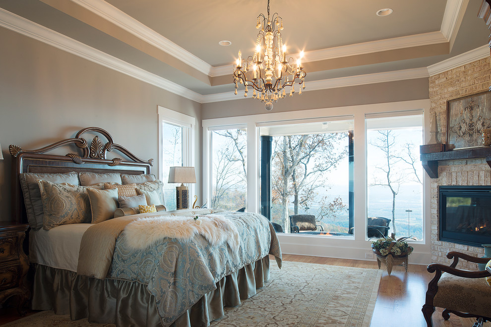Mid-sized traditional master bedroom in Other with grey walls, medium hardwood floors, a corner fireplace and a stone fireplace surround.