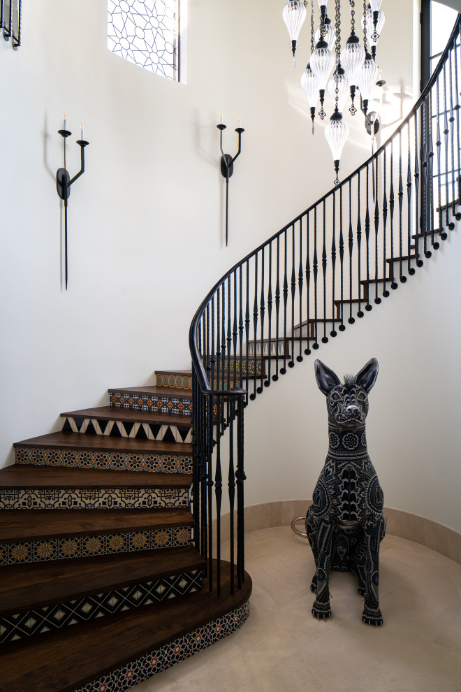 Idée de décoration pour un escalier courbe méditerranéen avec des marches en bois, des contremarches carrelées et un garde-corps en métal.