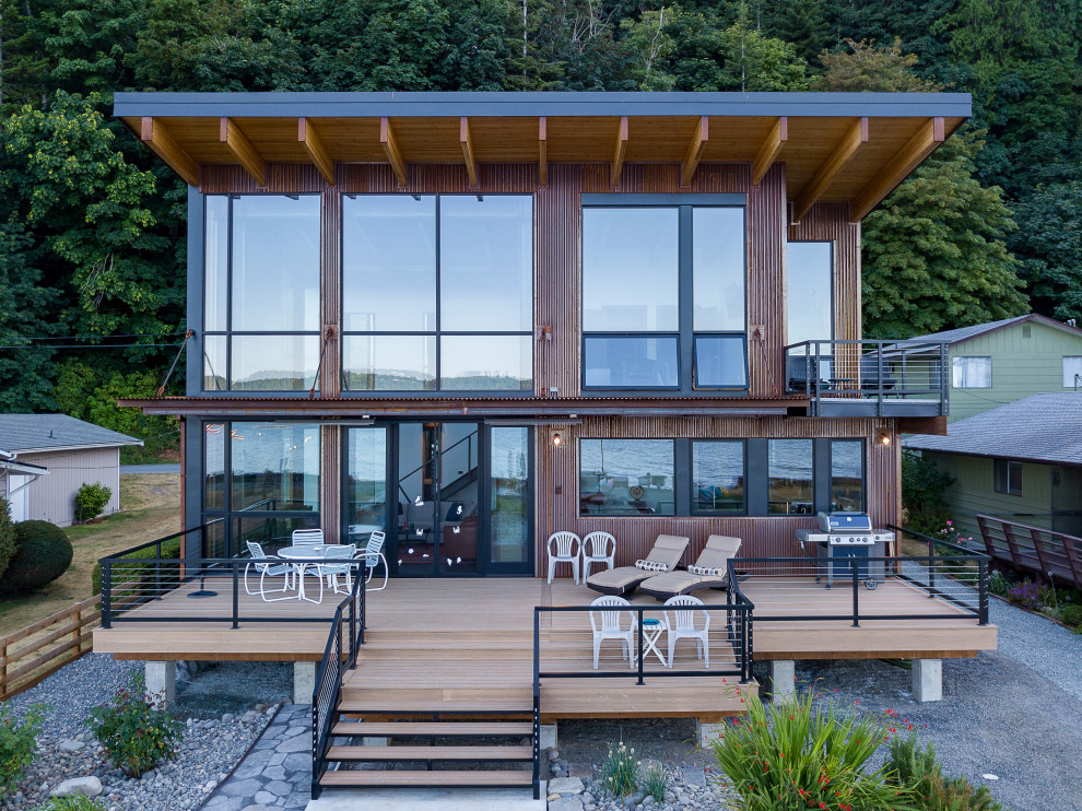 Стильный дизайн: двухэтажный, коричневый частный загородный дом среднего размера в стиле модернизм с односкатной крышей, металлической крышей и черной крышей - последний тренд