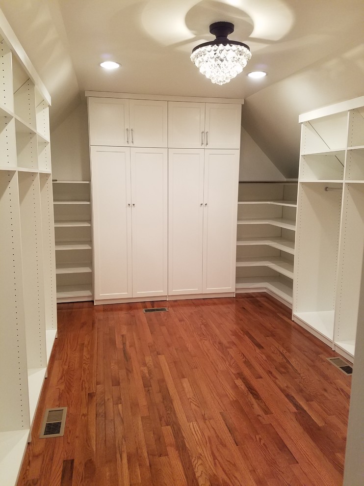 Mid-sized walk-in wardrobe in Chicago with shaker cabinets, white cabinets, medium hardwood floors and brown floor.