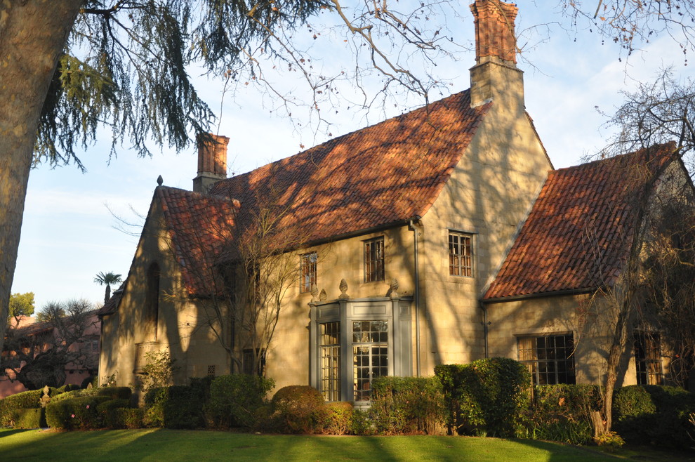 This is an example of a large traditional two-storey exterior in Sacramento with stone veneer and a tile roof.
