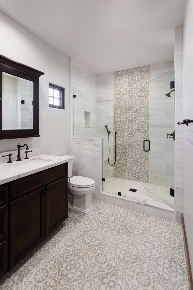 Inspiration for a mediterranean 3/4 bathroom in San Diego with dark wood cabinets, an alcove shower, a two-piece toilet, beige tile, gray tile, white tile, grey walls, an undermount sink, multi-coloured floor, a hinged shower door, white benchtops and recessed-panel cabinets.