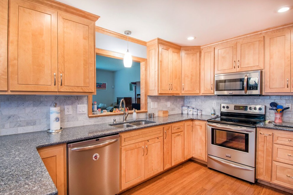 Mid-sized transitional u-shaped bamboo floor and brown floor enclosed kitchen photo in Cincinnati with a double-bowl sink, shaker cabinets, light wood cabinets, granite countertops, gray backsplash, marble backsplash, stainless steel appliances, a peninsula and gray countertops