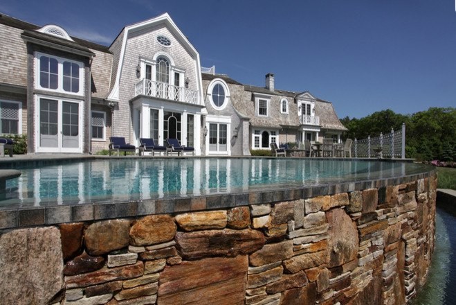 Large backyard stone and custom-shaped infinity hot tub photo in Boston