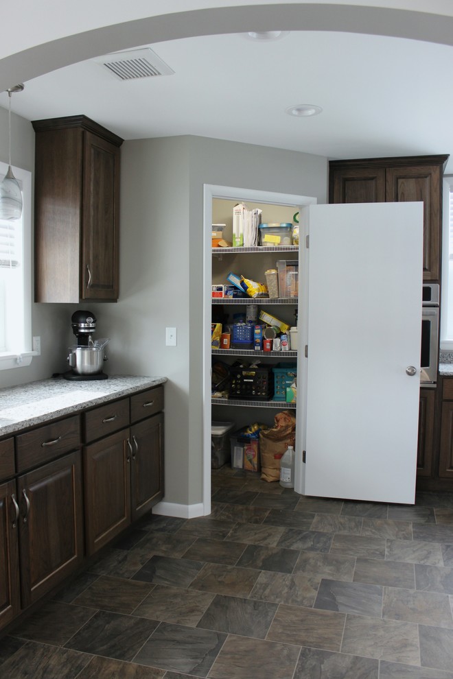 Enclosed kitchen - large transitional linoleum floor enclosed kitchen idea in Philadelphia with an undermount sink, raised-panel cabinets, dark wood cabinets, quartz countertops, stainless steel appliances and a peninsula