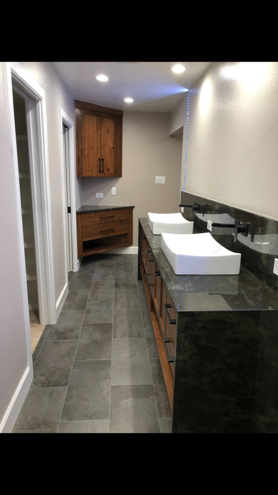 Photo of a mid-sized modern master bathroom in Other with furniture-like cabinets, brown cabinets, an open shower, a two-piece toilet, white tile, ceramic tile, brown walls, ceramic floors, a console sink, granite benchtops, grey floor, a hinged shower door and black benchtops.