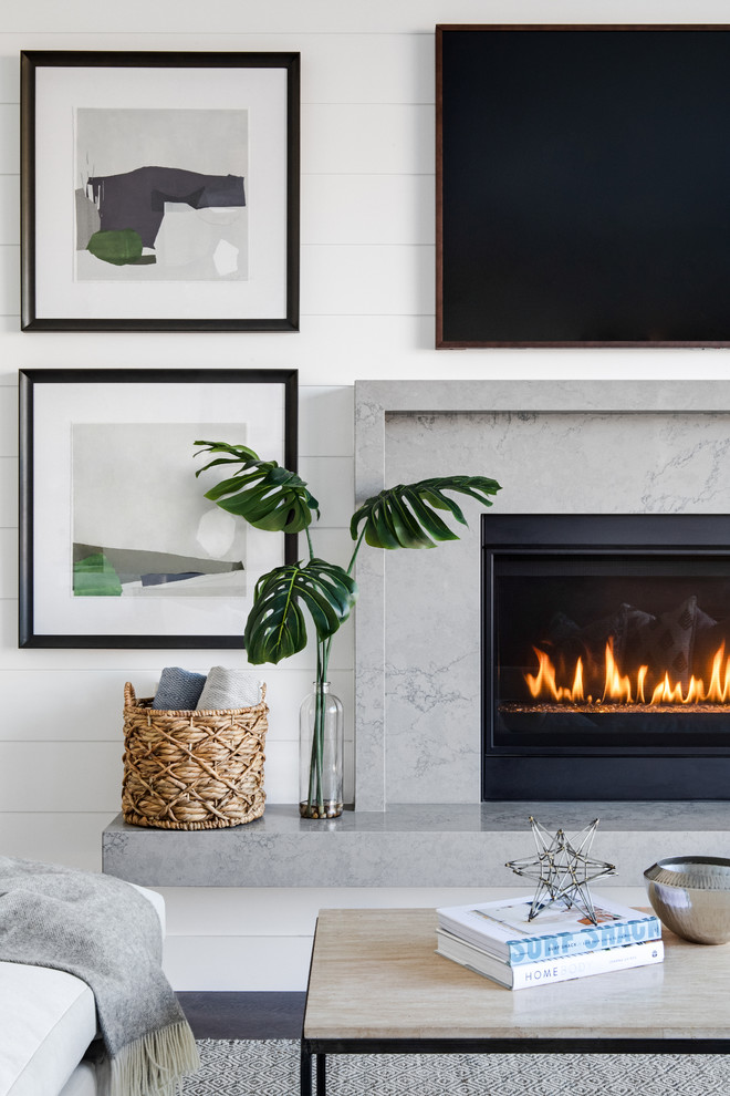 Inspiration for a mid-sized beach style open concept living room in Los Angeles with white walls, medium hardwood floors, a standard fireplace, a stone fireplace surround, a wall-mounted tv and brown floor.