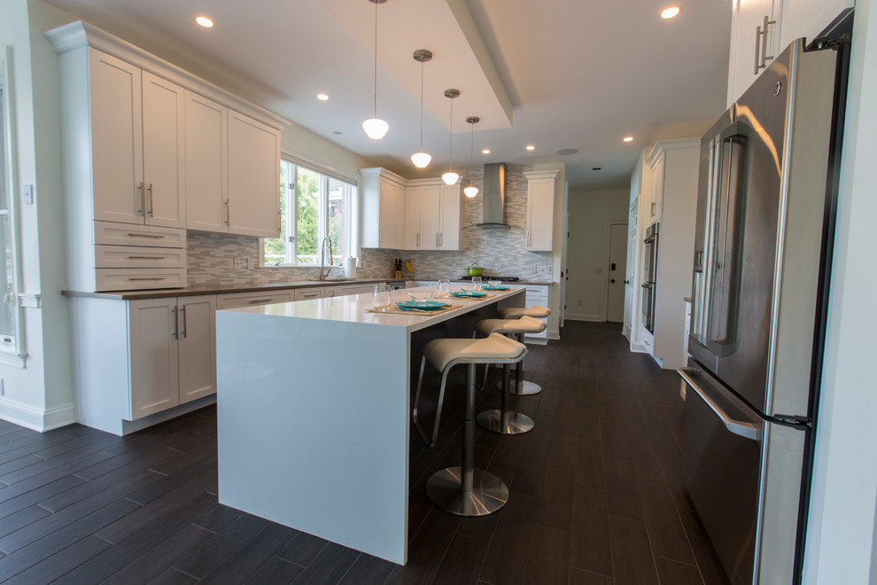 Design ideas for an expansive contemporary l-shaped open plan kitchen in Bridgeport with an undermount sink, shaker cabinets, white cabinets, quartz benchtops, white splashback, mosaic tile splashback, stainless steel appliances, porcelain floors and with island.