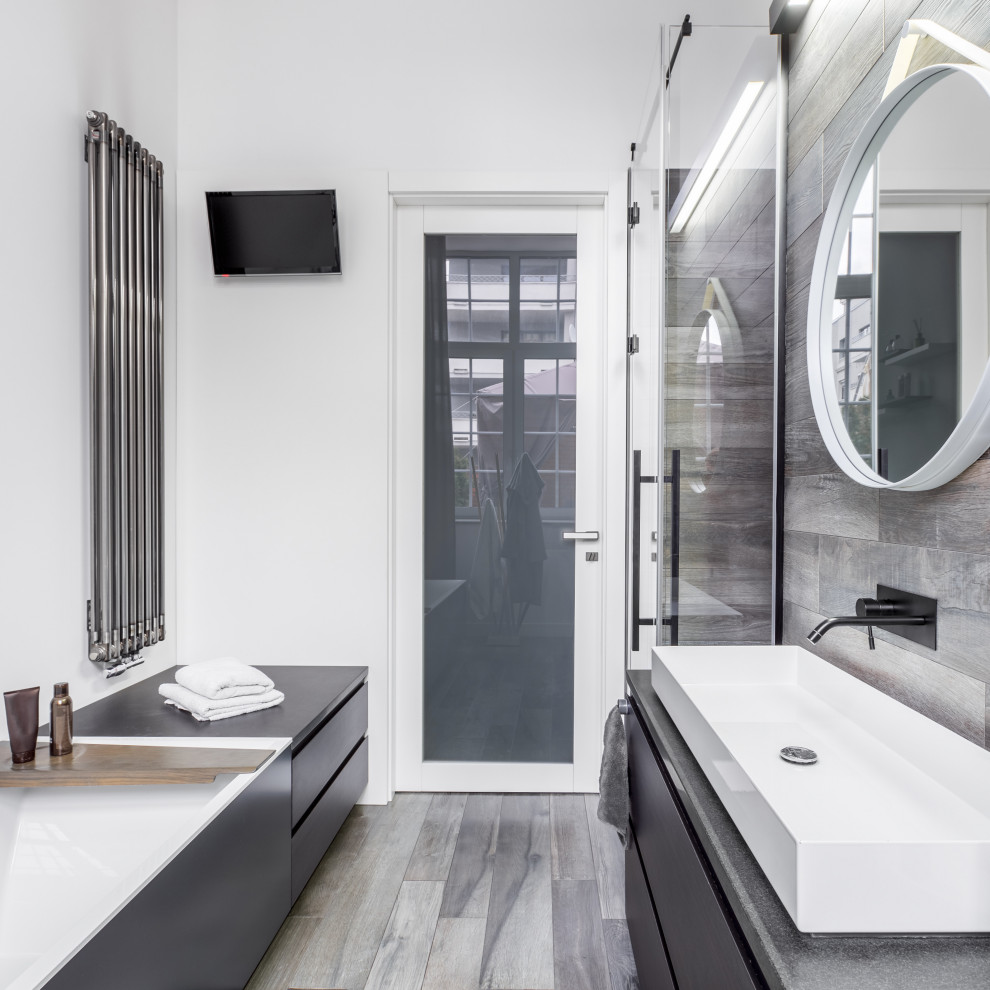 This is an example of a small modern master bathroom in New York with furniture-like cabinets, black cabinets, a hot tub, an open shower, a bidet, gray tile, wood-look tile, white walls, wood-look tile, a vessel sink, engineered quartz benchtops, grey floor, a hinged shower door, grey benchtops, a single vanity and a floating vanity.
