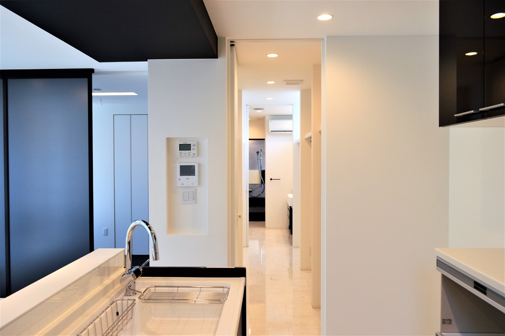 Photo of a modern single-wall open plan kitchen in Other with an undermount sink, beaded inset cabinets, black cabinets, solid surface benchtops, white splashback, plywood floors, no island, white floor and white benchtop.