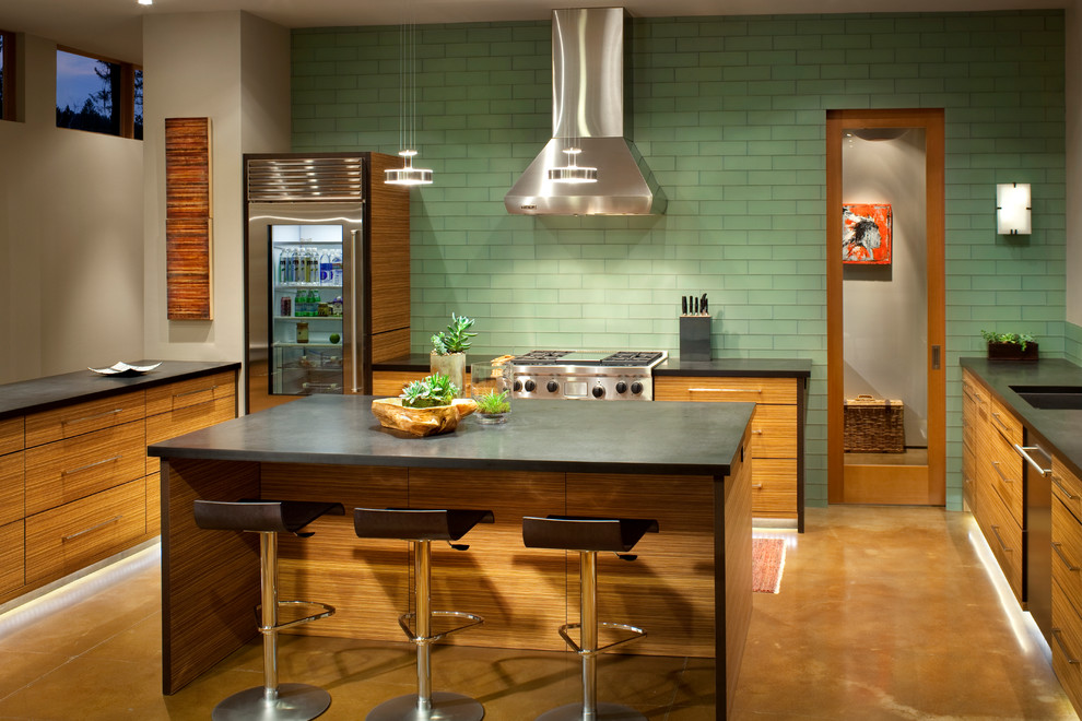 Photo of a large contemporary u-shaped eat-in kitchen in Other with an undermount sink, flat-panel cabinets, medium wood cabinets, green splashback, glass tile splashback, stainless steel appliances, concrete floors and with island.
