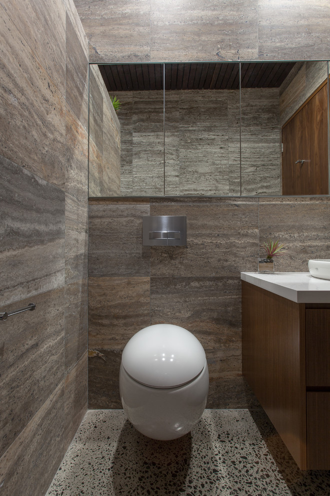 Design ideas for a mid-sized modern master bathroom in Sydney with flat-panel cabinets, medium wood cabinets, an open shower, a wall-mount toilet, brown tile, travertine, brown walls, concrete floors, a drop-in sink, engineered quartz benchtops, grey floor and white benchtops.