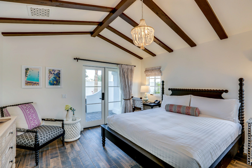 This is an example of a mediterranean master bedroom in Los Angeles with beige walls, dark hardwood floors and brown floor.