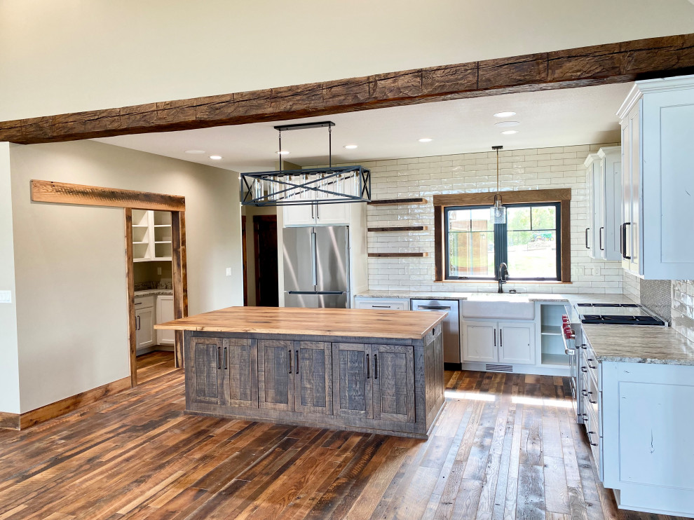 Design ideas for a mid-sized country l-shaped open plan kitchen in Kansas City with a farmhouse sink, shaker cabinets, dark wood cabinets, wood benchtops, white splashback, shiplap splashback, stainless steel appliances, medium hardwood floors, with island, brown floor and brown benchtop.