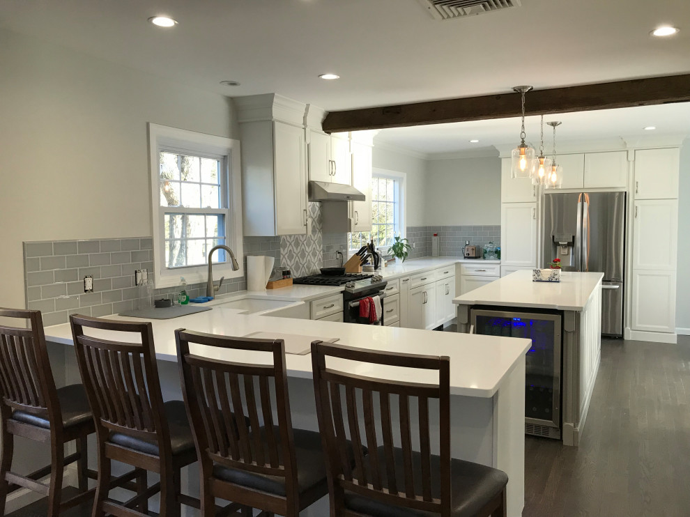 Large transitional u-shaped ceramic tile and gray floor eat-in kitchen photo with a farmhouse sink, recessed-panel cabinets, white cabinets, quartz countertops, gray backsplash, subway tile backsplash, stainless steel appliances, an island and white countertops