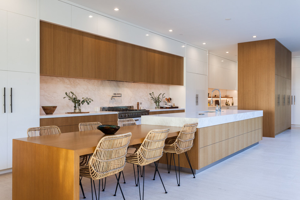 Expansive contemporary single-wall eat-in kitchen in Orange County with flat-panel cabinets, medium wood cabinets, beige splashback, with island, white benchtop, an undermount sink, marble benchtops, marble splashback, panelled appliances, marble floors and beige floor.