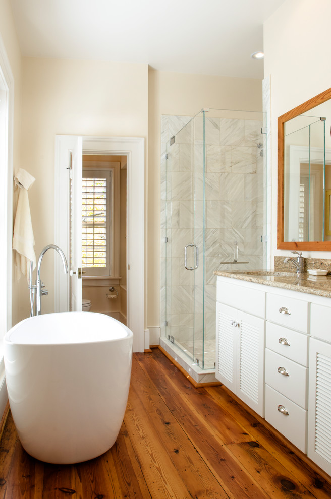 Transitional bathroom in Other with white cabinets, a freestanding tub, a corner shower, beige tile, beige walls, medium hardwood floors, an undermount sink, brown floor, a hinged shower door and beige benchtops.