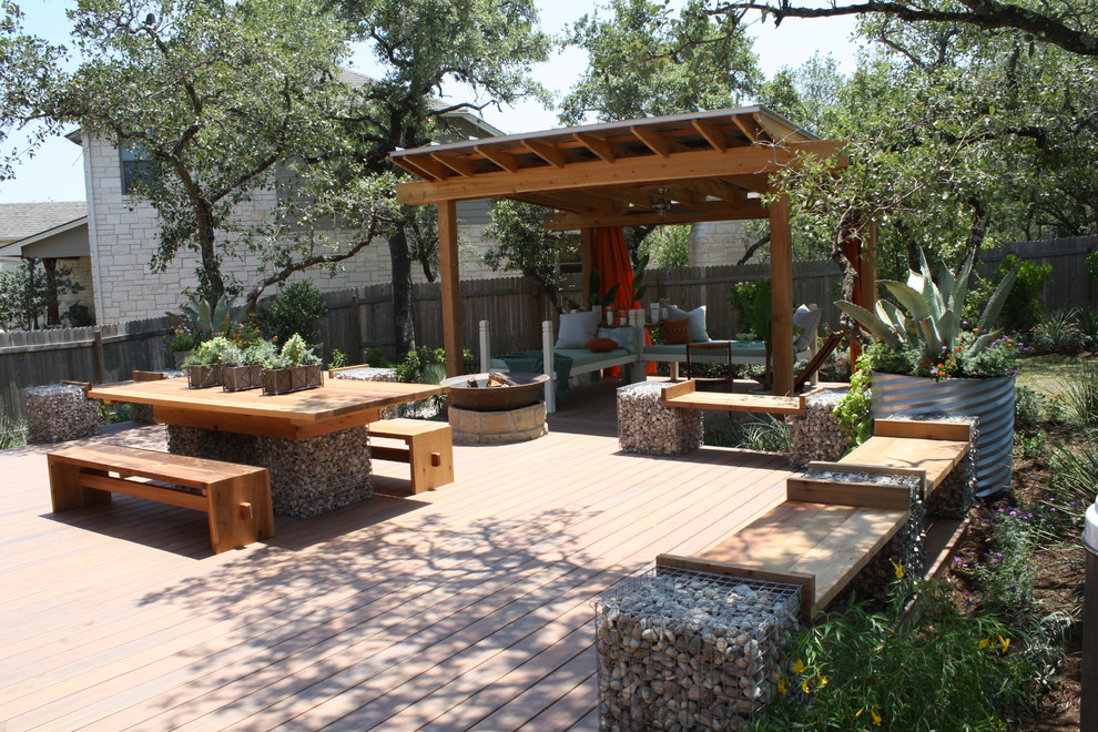 Large modern backyard patio in Austin with a fire feature, decking and a pergola.