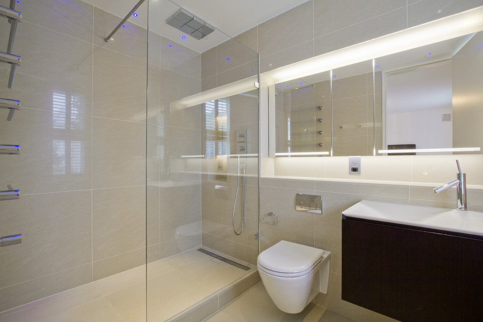 Photo of a contemporary bathroom in London with furniture-like cabinets, dark wood cabinets, solid surface benchtops, beige tile, porcelain tile, an open shower, a wall-mount toilet, a wall-mount sink and porcelain floors.