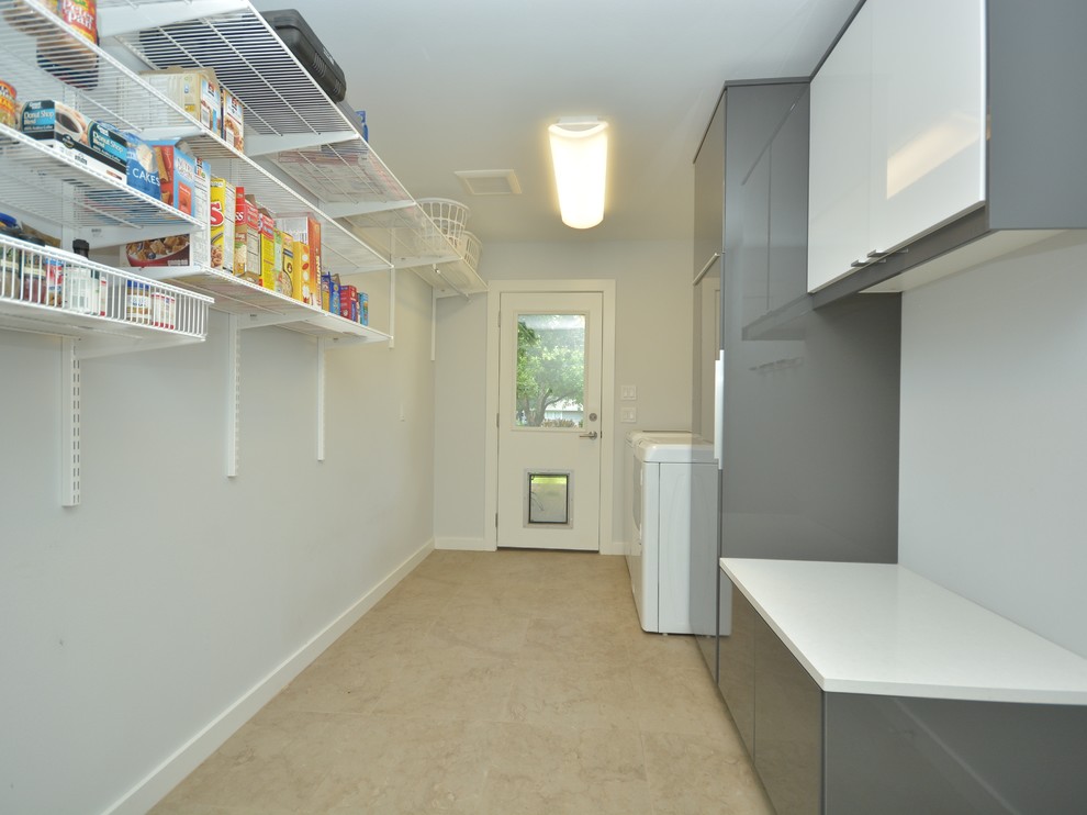 Large contemporary galley dedicated laundry room in Austin with shaker cabinets, grey cabinets, solid surface benchtops, white walls, ceramic floors and a side-by-side washer and dryer.