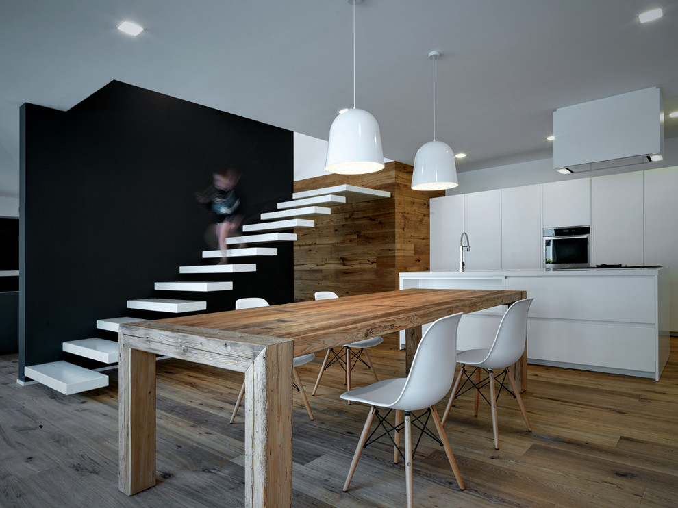 Inspiration for a contemporary dining room in Milan with black walls, medium hardwood floors and no fireplace.