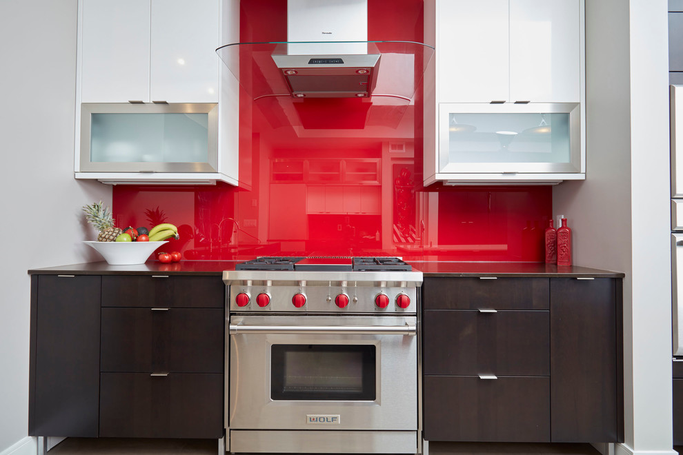 Mid-sized contemporary single-wall kitchen in Toronto with a farmhouse sink, quartz benchtops, red splashback, glass sheet splashback, stainless steel appliances, with island, flat-panel cabinets and dark wood cabinets.
