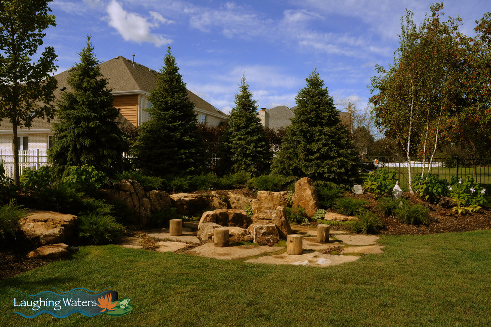 Photo of a mid-sized country backyard partial sun xeriscape for fall in Chicago with a fire feature and natural stone pavers.