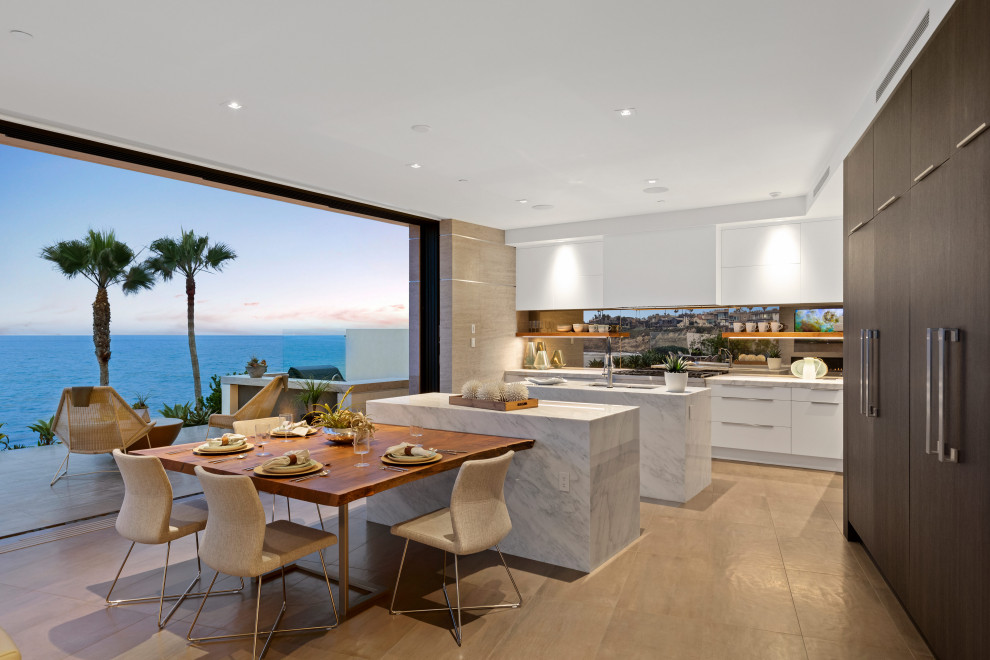 Mid-sized contemporary galley open plan kitchen in San Diego with a drop-in sink, flat-panel cabinets, white cabinets, marble benchtops, brown splashback, timber splashback, stainless steel appliances, ceramic floors, multiple islands, beige floor and white benchtop.