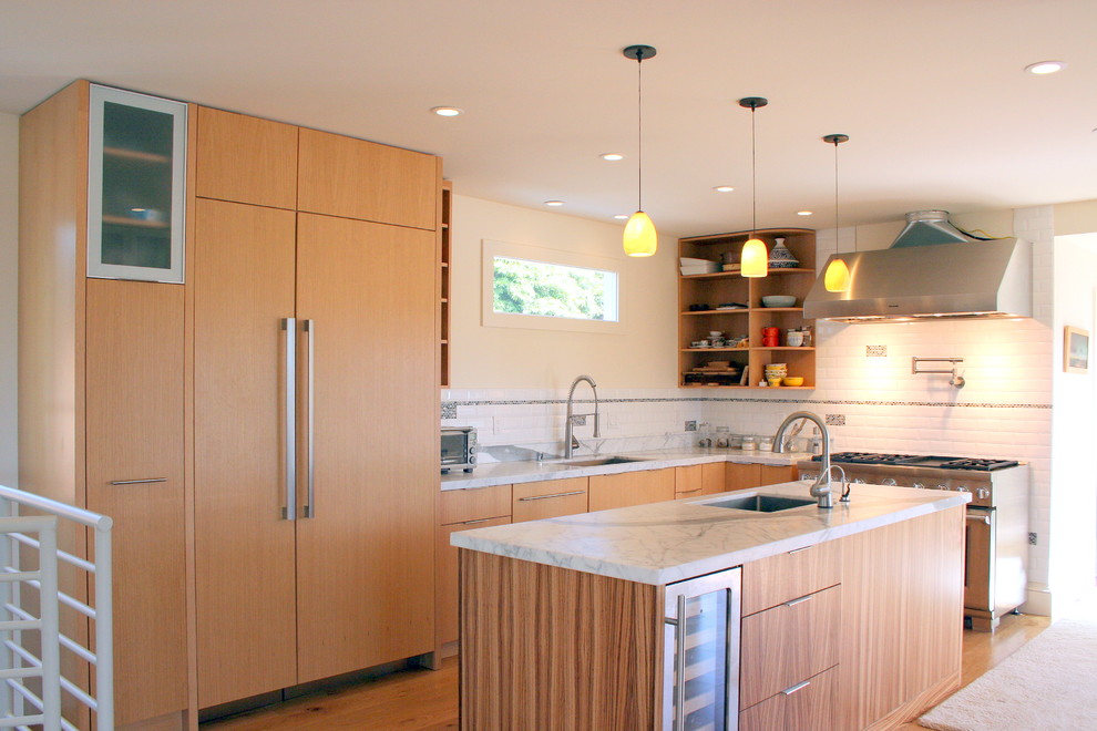 This is an example of a large contemporary l-shaped eat-in kitchen in San Francisco with an undermount sink, flat-panel cabinets, light wood cabinets, marble benchtops, white splashback, ceramic splashback, stainless steel appliances, medium hardwood floors and with island.