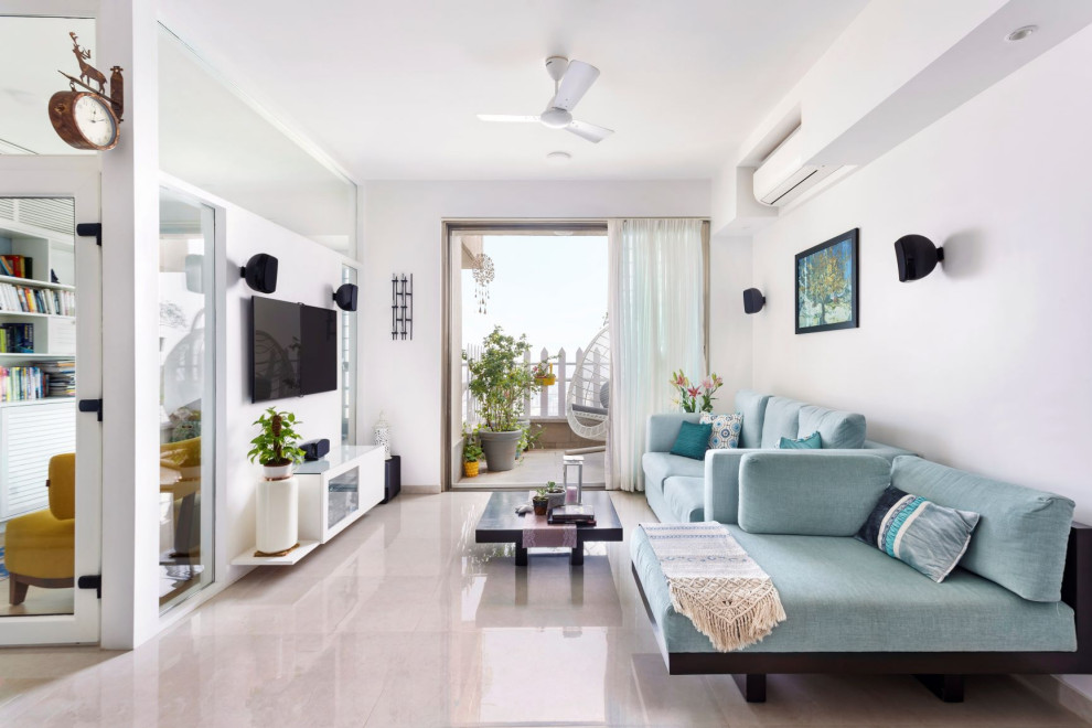 This is an example of a contemporary living room in Mumbai with white walls, a wall-mounted tv and grey floor.